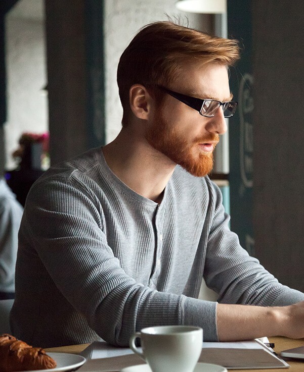 A man sitting at a table with a laptop and a cup of coffee.