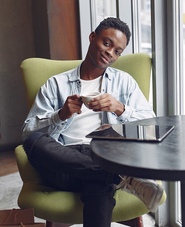 A young man sitting in a chair and using his phone.