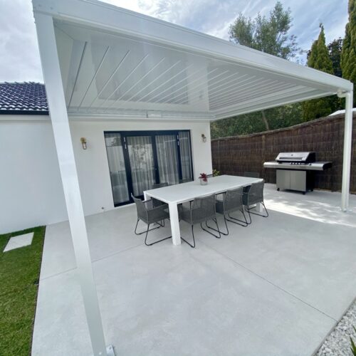 A white covered patio with a table and chairs.