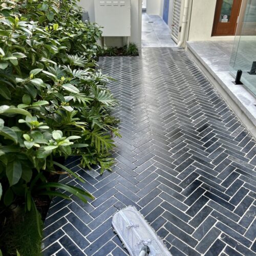 A herringbone tiled walkway being cleaned with a mop.