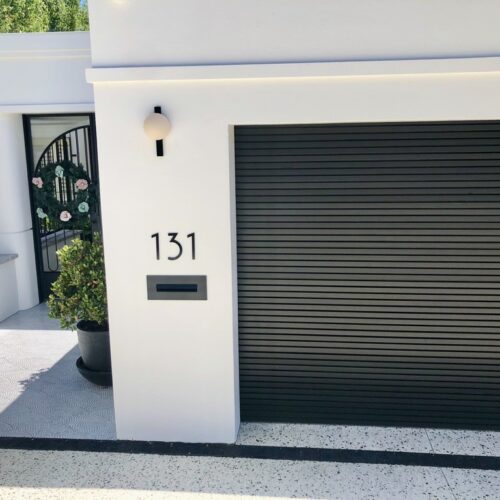 A black garage door with a number on it.