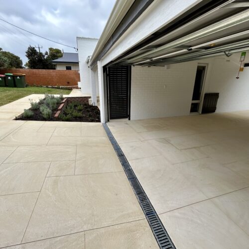 A driveway with a white tiled floor and a garage door.