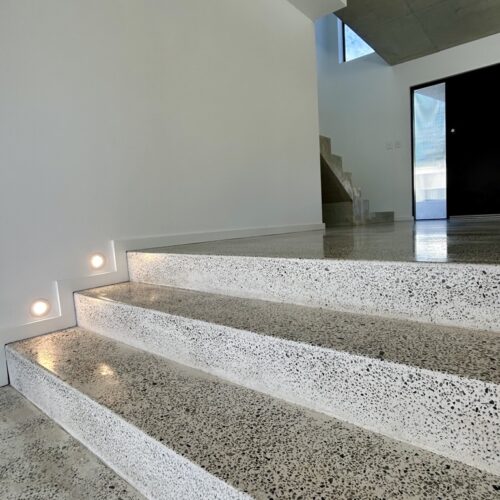 A concrete staircase in a house with lights on it.