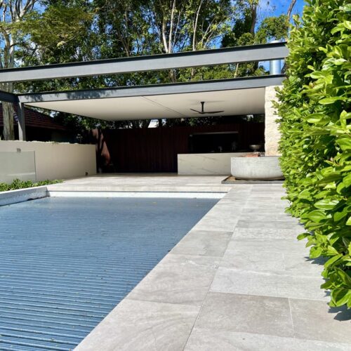 A modern backyard with a swimming pool and bushes.