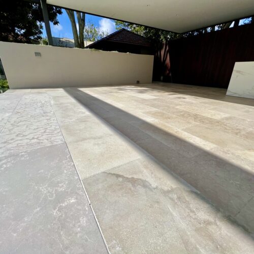 A white tiled patio in a backyard.