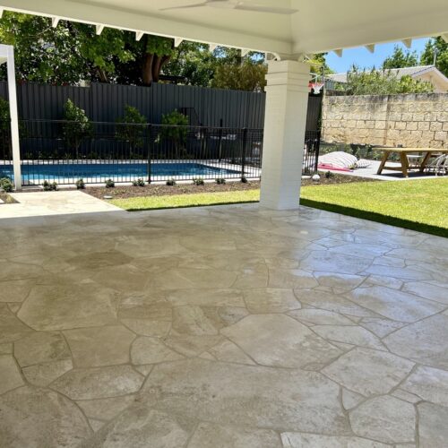 A backyard with a white tiled patio and a pool.