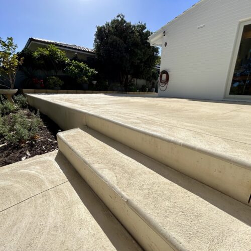 A concrete patio with steps leading up to a house.