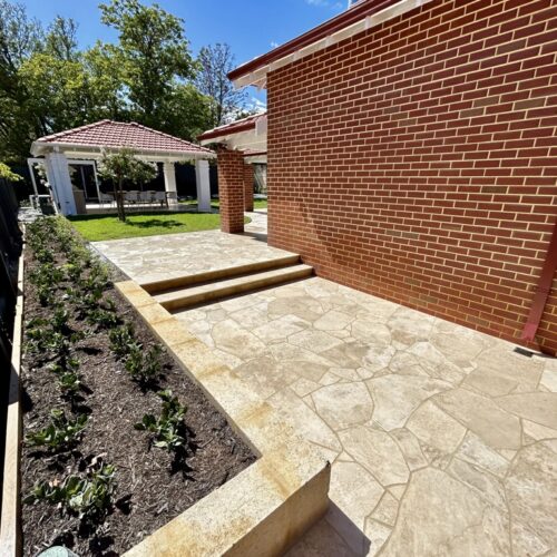 A backyard with a brick wall and steps.