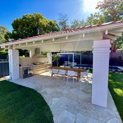 A backyard with an outdoor kitchen and dining area.