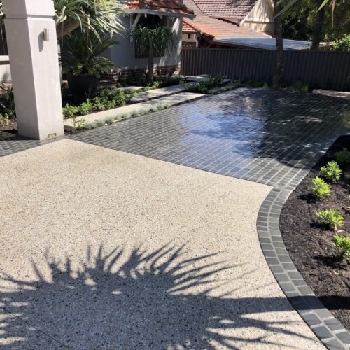 A concrete driveway with a palm tree in the background.