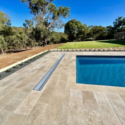 A swimming pool in a backyard with grass and trees.