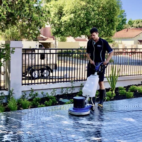 A man cleaning a patio with a pressure washer.