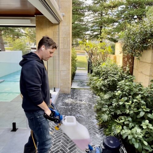 A man cleaning a patio with a pressure washer.