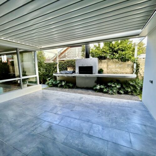 A patio with a tiled floor and a fireplace.