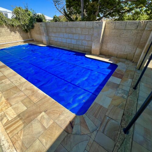 A blue swimming pool in a backyard.