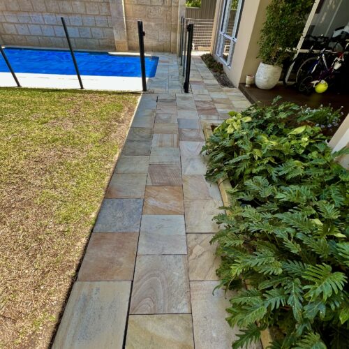 A walkway leading to a pool in a backyard.