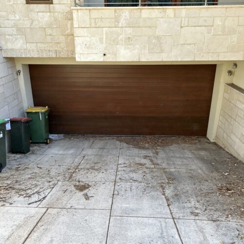 A wooden garage door with two trash cans.