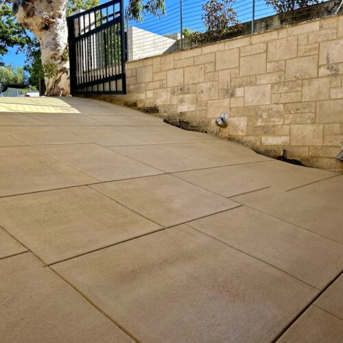 A patio with a stone walkway and a fence.