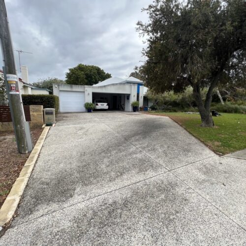 A street view of a house with a driveway and a garage.