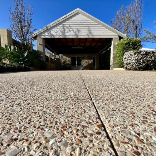 A driveway with gravel and stones in front of a house.