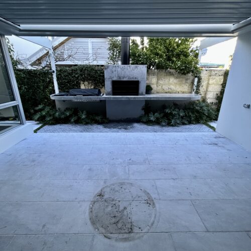 A white tiled patio with a fireplace in the middle.