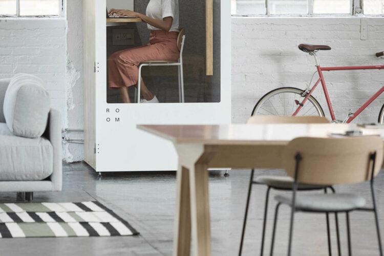 A woman sits at a desk in a room with a bicycle.